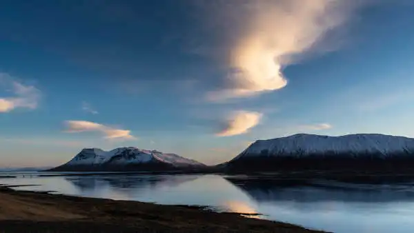 Sunset over a fjord in the winter time, mountains are covered with snow